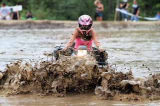 Woman riding an ATV through a mud pit
